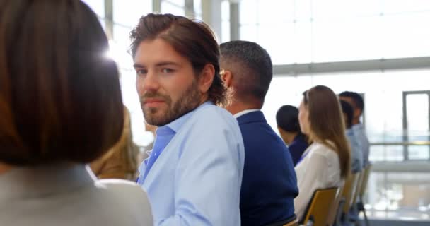 カメラに笑顔とビジネス セミナー に座っている白人実業家の側面図 — ストック動画