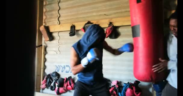 年轻的非洲裔美国男拳击手在健身工作室与教练练习拳击的侧视图 他正在打打气筒4K — 图库视频影像