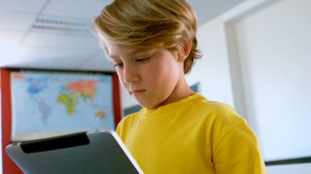 学校の教室でデジタル タブレットを使用してかわいい白人少年の正面 を学習 研究しています — ストック動画