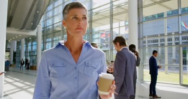 一个白种人女商人在办公室大厅里散步时拿着咖啡的前面看着4K — 图库视频影像