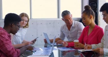 Ofisteki bir toplantıda grafikler üzerinde tartışan çok ırklı iş arkadaşlarının yan görünümü. Modern ofiste birlikte çalışıyorlar. 