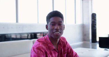 Portre yakışıklı Afro-Amerikan erkek executive ofis lobisinde oturan. O gülümseyen ve kameraya 4 k arıyorsunuz