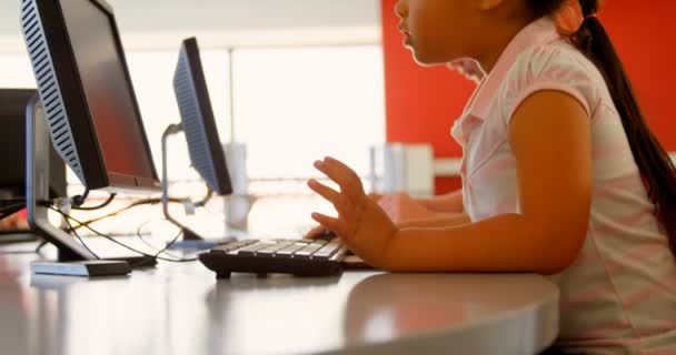 在学校用电脑学习的混合种族女学生的侧视图 她坐在办公桌前 — 图库视频影像