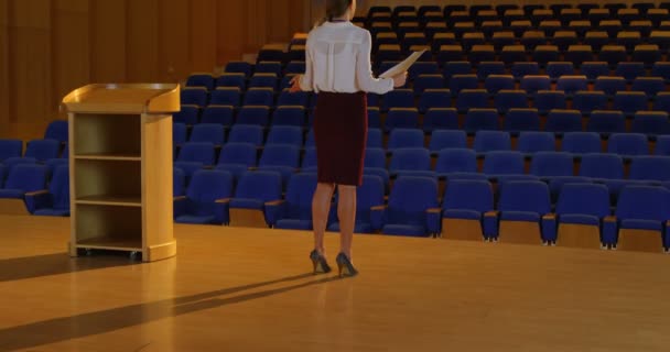 若い白人実業家空の講堂でスピーチの練習のリアビュー 彼女は 立っている を身振りで示すこと — ストック動画