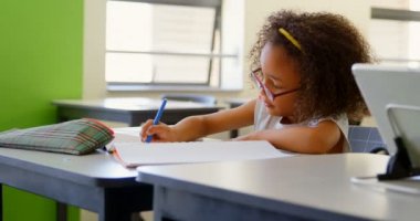 Yan masada oturan ve sınıfta okuyan tatlı Afro-Amerikan kız öğrenci bir bakış. Bir dizüstü bilgisayarda 4 k yazıyor