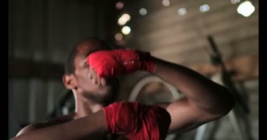 Genç Afro-Amerikan erkek boksör boks fitness salonunda pratik önden görünümü. O kum torbası 4 k vuruyor