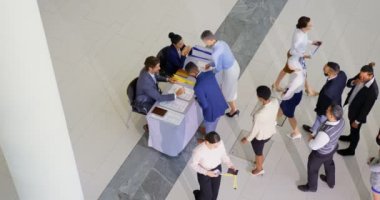 Konferans kayıt tablosunu 4 k iade etmeden önce sırada bekleyen iş adamları yüksek açılı görünüş