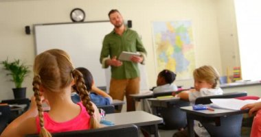 Okulda sınıfta okuyan çok etnik okul çocuklarının arka görünümü. Erkek okul öğretmeni öğretim öğrenciler 4k