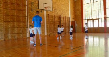Arkadan görünüş yakışıklı erkek basketbol antrenör Basketbol basketbol sahası içinde schoolkids için öğretim. Basketbol 4 k atma kız öğrenci