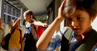 İlköğretim koridorunda üzücü bir karışık yarış çocuğu zorbalık çeşitli okul çocukları grubun ön görünümü. Koridor 4k ayakta Schoolboy