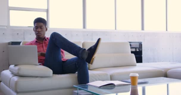 Handosme アフリカ系アメリカ人の男性幹部は 近代的なオフィスにラップトップを使用しての正面 のロビーで座っています — ストック動画
