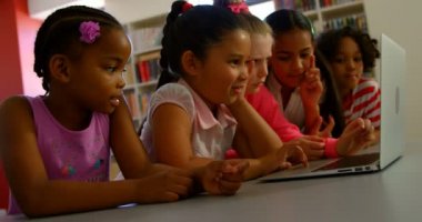 Masada dizüstü bilgisayar üzerinde birlikte okuyan çeşitli okul çocukları grup yan görünümü. Dizüstü 4k kullanırken gülümsüyorlar