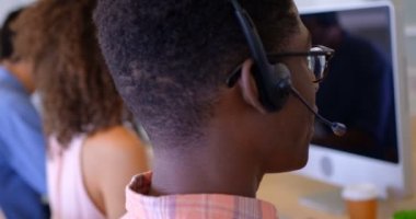 Genç çok etnik gruptan oluşan müşteri Satış Yöneticiler modern ofis içinde kulaklık konuşurken yan görünüm. 4 k masada birlikte çalıştıkları