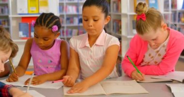 Okul kütüphanesinde masada birlikte okuyan çeşitli okul çocukları grubunun ön görünümü. Onların classwork 4k dozlama