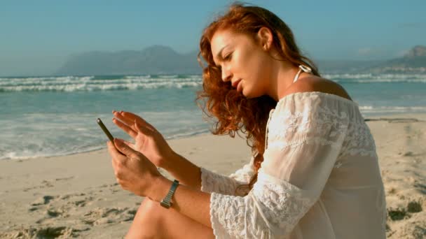 年轻的高加索妇女坐在那里 手牵着手在阳光下在海滩上穿过头发 在阳光下4K 的侧视图 — 图库视频影像