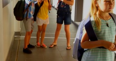 İlkokul koridorunda üzgün Kafkas kız zorbalık çeşitli okul çocukları grubun ön görünümü. Beyaz kız elleriyle 4k yüzünü kapsayan