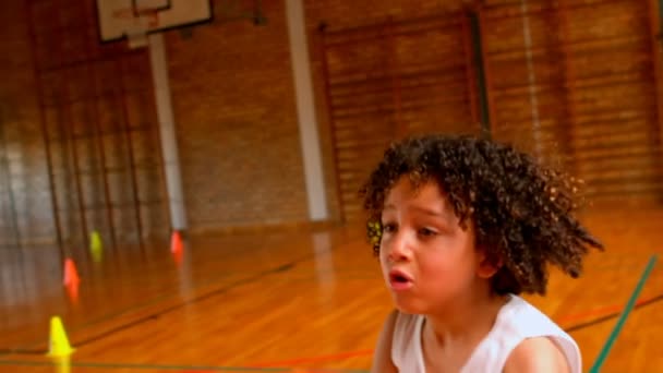学校でバスケット ボールのコートでバスケット ボールで遊んで運動のアフリカ系アメリカ人の少年の側面図です 彼はサッカー を投げています — ストック動画