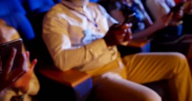 Yan görünümü çok etnik gruptan oluşan iş adamları iş seminer oditoryum sırasında cep telefonu kullanarak. Mesaj metni 4 k olduklarını