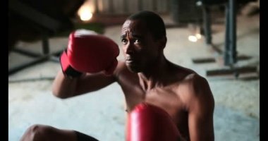 Genç Afro-Amerikan erkek boksör boks eğitmen fitness salonunda ile pratik önden görünümü. Sit yaparken el yumruk pratiği yapıyor 4 k ups