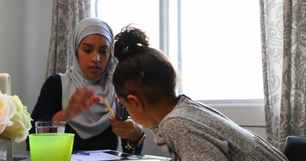 若いアジアの母 ヒジャーブを着て 娘の宿題を手伝ってホーム で図面をスケッチしての正面図 — ストック動画