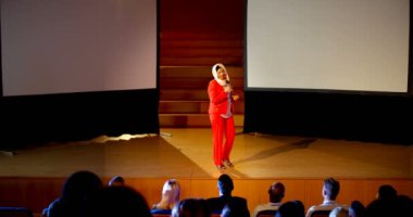 Konferans salonu iş seminerde konuşan güzel olgun beyaz hijab işkadını önden görünümü. Seyirci onun 4 k için dinleme