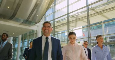 Birlikte yürüyüş ofis lobisinde 4 k mutlu karışık ırk iş adamları Önden Görünüm