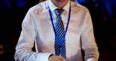 Oditoryumda iş semineri sırasında dijital tablet kullanan Genç Asyalı işadamının ön görünümü. Gülümsüyor ve kameraya bakıyor. 