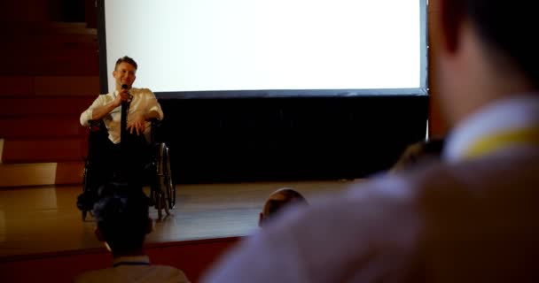 在礼堂举行的商业研讨会上 手持手感的年轻白种残疾商人的前方视图 他坐在轮椅上 — 图库视频影像