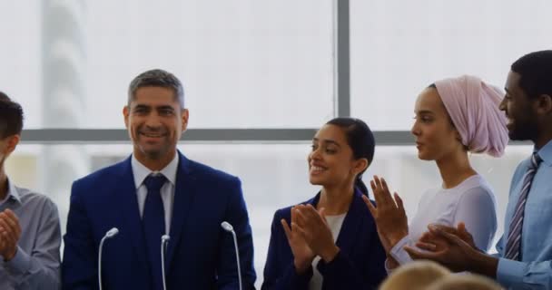 公開ビジネス セミナー で彼に拍手でしている間彼の同僚と共に表彰台に立っている白人実業家の正面図 — ストック動画