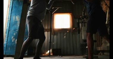 Genç Afro-Amerikan erkek boksör boks spor salonunda antrenör ile pratik düşük açılı görünümü. El yumruk 4 k pratiği yapıyor