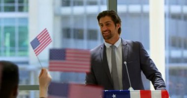 4k iş seminerinde Amerikan bayrakları yükselten halka konuşan kafkas bir erkek konuşmacının ön görünümü