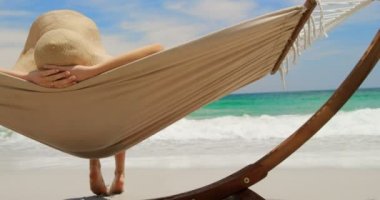 Sahilde bir hamakta dinlenen Kafkas kadının arka görünümü. O başının arkasında 4k elleri ile yatıyor