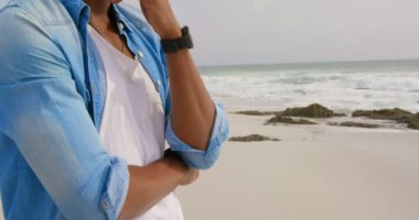 Sahilde çenesi üzerinde el ile duran Afrikalı Amerikalı adamın yan görünümü. O 4k uzağa bakıyor