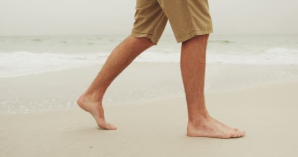 ビーチで裸足で歩く男の低いセクション 背景の海の波 — ストック動画