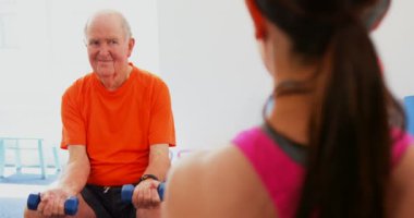 Fitness stüdyosunda egzersiz kadın eğitmen eğitim kıdemli adam Arka görünüm. Halter kullanıyorlar. 