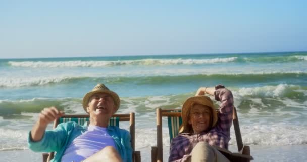 活跃高级白种人夫妇在海滩的日光浴躺椅上玩乐的前视图 他们在4K的太阳躺椅上放松 — 图库视频影像