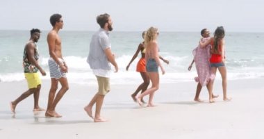 Sahilde yürüyen karışık ırk lı arkadaşların yan görünümü. Onlar eğlenceli 4k yaşıyorsanız