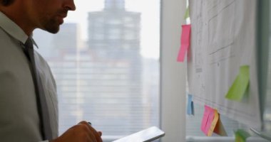 Modern ofiste cam tahta üzerinde plan üzerinde çalışan genç Kafkas erkek yöneticiyan görünümü. Dijital tablet kullanıyor. 