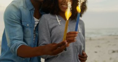 Sahilde elinde kıvılcım tutan Afrikalı-Amerikalı çift ön görünümü. Onlar eğlenceli 4k yaşıyorsanız