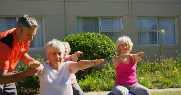 白种人男性培训师在疗养院花园对老年人进行瑜伽表演方面的培训 他们在一起练习4K — 图库视频影像