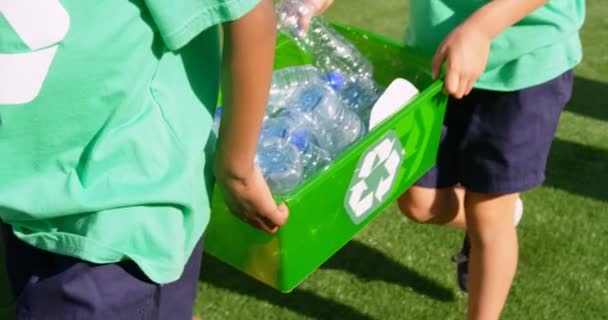 在学校操场上 有一群学生携带塑料瓶垃圾 他们正在研究瓶子回收 — 图库视频影像