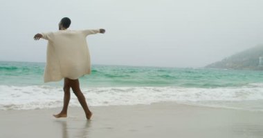 Genç Afrikalı Amerikalı kadın sahilde dans ediyor. Çok eğleniyor.