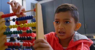 Asyalı öğrenci nin okulda ki bir sınıfta abaküs ile matematik problemini çözmesinin ön görünümü. Boncukları 4k sayıyor.