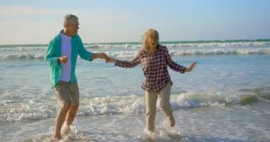 Aktif kıdemli Kafkas çiftinin sahilde birlikte dans ederken ki yan görünümü. Onlar eğlenceli 4k yaşıyorsanız