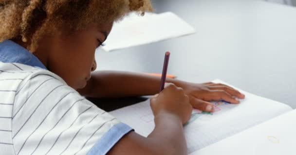 在教室里的笔记本上画一幅美国非洲人的素描 他坐在4K的桌子上 — 图库视频影像