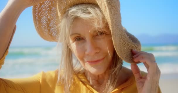 站在海滩上的活跃高级白种妇女站在沙滩上的正面景色 她微笑着看着相机4K — 图库视频影像