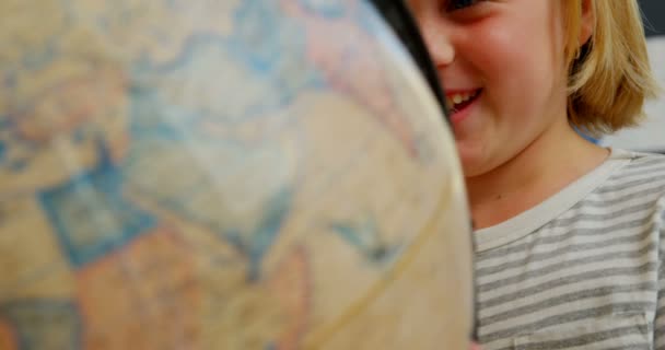 在学校教室的课桌前 快乐的白种女学生正在学习地球仪 她正在寻找和旋转地球4K — 图库视频影像