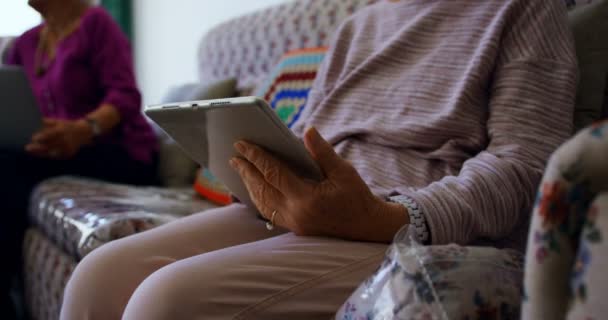 老人ホームでデジタルタブレットを使用してアクティブなシニア女性のミッドセクション 彼女はソファに座っている — ストック動画