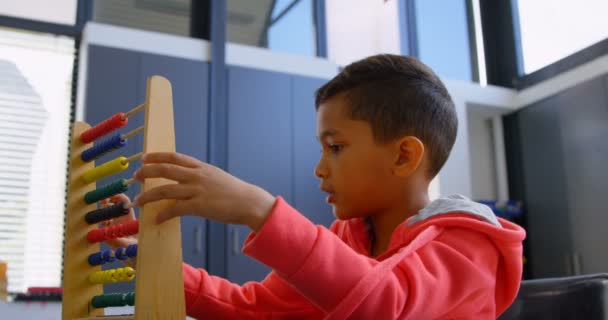 학교에서 교실에서 책상에서 주폐물로 문제를 해결하는 아시아 남학생의 측면보기 4K를 — 비디오