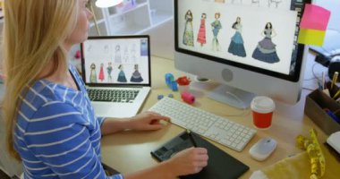 Ofiste masada grafik tablet kullanarak Kafkas kadın moda tasarımcısı yan görünümü. O bilgisayar 4k bakıyor